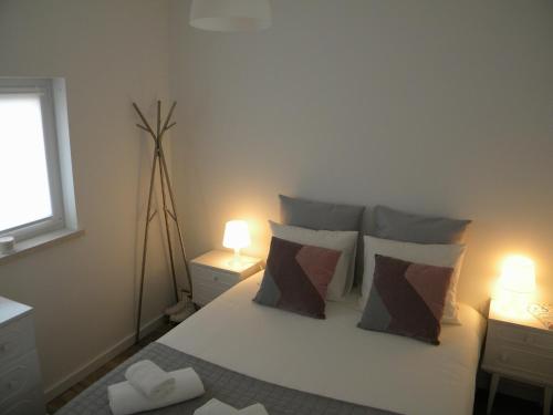 sypialnia z łóżkiem z poduszkami i 2 lampami w obiekcie Serra da Pescaria House - Nazaré w mieście Nazaré
