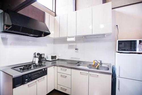 a white kitchen with a sink and a microwave at Maeniiya Machiya Inn in Kyoto