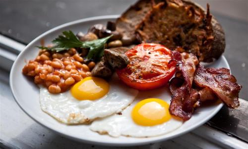 a plate of breakfast food with eggs bacon beans and toast at Dairy Cottage Luxury B&B in Attleborough