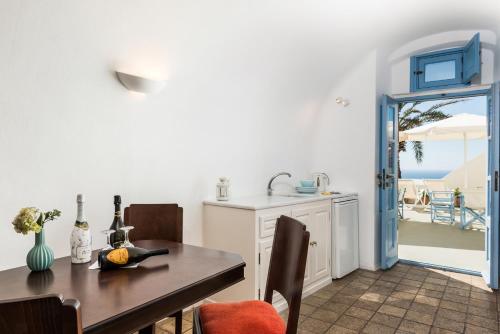 a dining room with a table and a kitchen with a view at Pantelia Suites in Fira