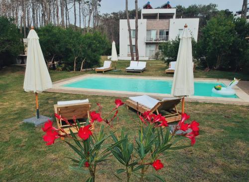 a swimming pool with two umbrellas and red flowers at Pinar del Oriental in José Ignacio