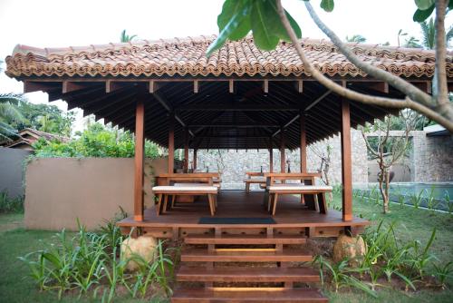 a gazebo with benches and tables in a garden at The Villa by Contemporary Ceylon in Wadduwa