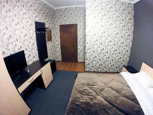 a bedroom with a bed and a desk and a door at Mini-Hotel Pulsar in Astana