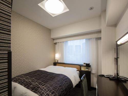 een kleine slaapkamer met een bed en een raam bij APA Hotel Kanda Ekimae in Tokyo