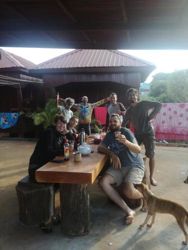 a group of people sitting around a table with a dog at Bee Bee's Chalets home stay and trekking in Banlung