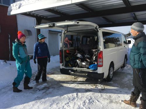 a group of people standing next to a van in the snow at Santari in Shintoku