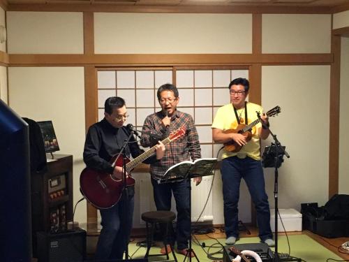 a group of three men playing instruments in a room at Santari in Shintoku