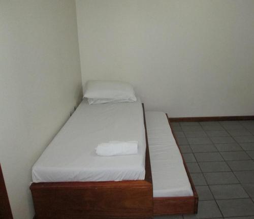 um pequeno quarto com uma cama com um colchão branco em Temporada Ponta das Canas em Florianópolis