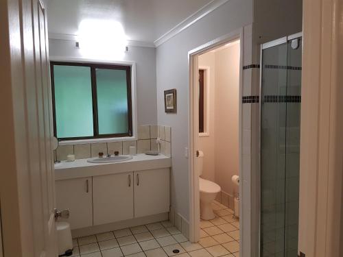 a bathroom with a sink and a toilet and a window at Beerwah House in Beerwah