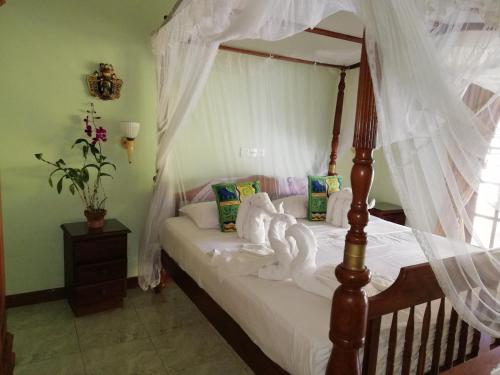 un dormitorio con cama con dosel y cisnes. en Mahi Villa, en Bentota