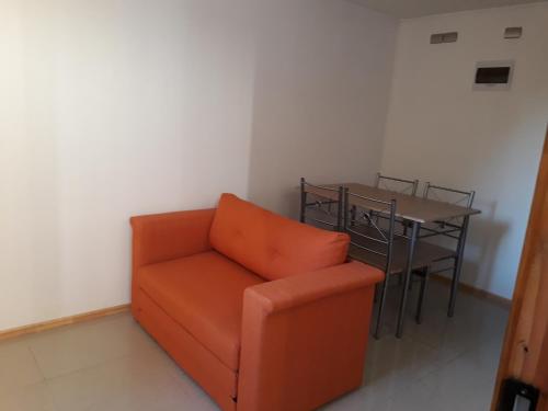 Un sofá naranja en una habitación con una mesa. en Los Arrayanes de Harnecker, en Valdivia