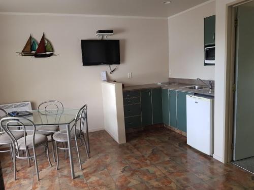 a kitchen with a table and chairs and a small kitchen at Portmans Motor Lodge in Hastings