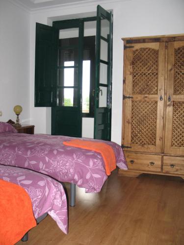 a bedroom with two beds and a wooden cabinet at Casa Rural La Dama del Alba in Vega de Magaz