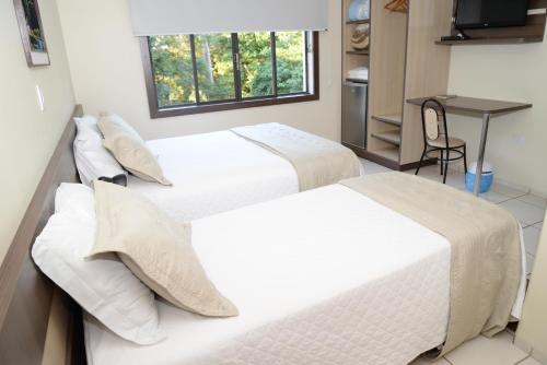 2 camas en una habitación con ventana en Palace Hotel Guaíra, en Guaíra