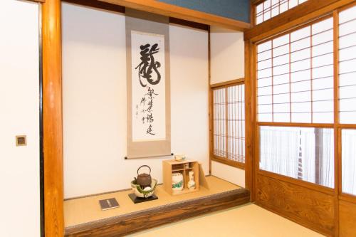 an oriental room with a room with a window and a shrine at Guest House Kyorakuya Kinkakuji in Kyoto