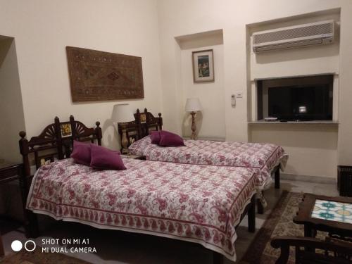 two beds in a hotel room with purple pillows at Hotel Meghniwas in Jaipur