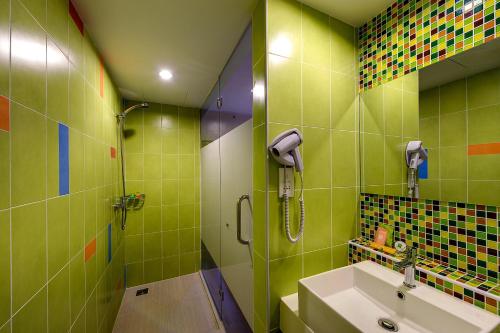 a green bathroom with a sink and a shower at Ibis Styles Kuala Lumpur Fraser Business Park in Kuala Lumpur