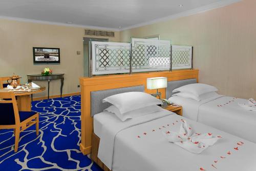 a hotel room with two beds and a table and a desk at Makkah Towers in Makkah