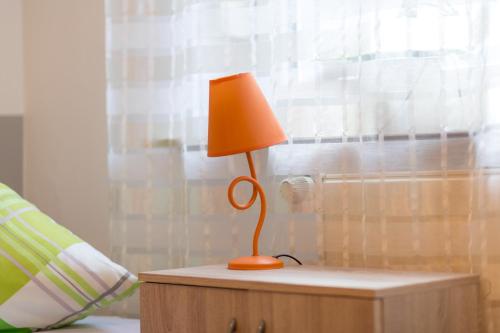 eine orangefarbene Lampe auf einem Tisch neben einem Bett in der Unterkunft Ferienwohnung Wideystrasse in Witten