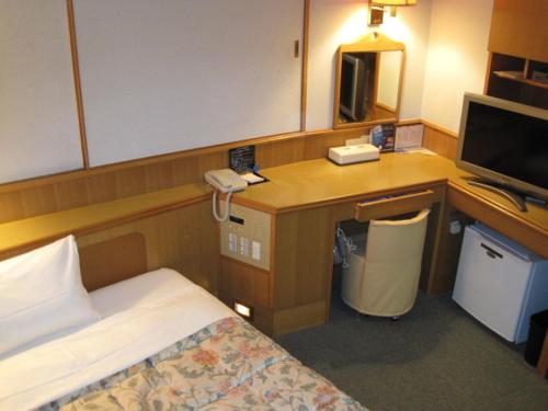 a hotel room with a bed and a desk with a phone at Hyuga Dai-ichi Hotel in Hyuga