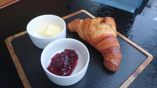 a tray with a loaf of bread and a bowl of butter and jam at Penzión v Inom Svete in Žilina