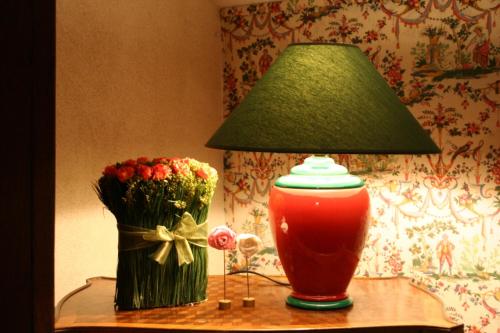 a lamp on a table next to a vase of flowers at Manoir de Pommery in Sixt-sur-Aff