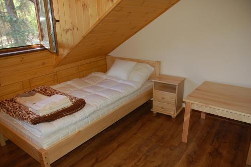 łóżko w drewnianym pokoju ze stołem w obiekcie Ostoja Spychowo w mieście Spychowo