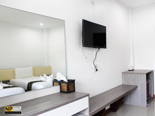 a hotel room with a bed and a tv on the wall at NP Hotel in Buriram