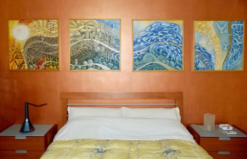 una camera da letto con 4 dipinti alle pareti e un letto di La collina degli Elimi a Valderice