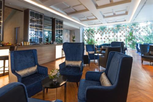 a waiting room with blue chairs and a bar at Lancaster Bangkok in Bangkok