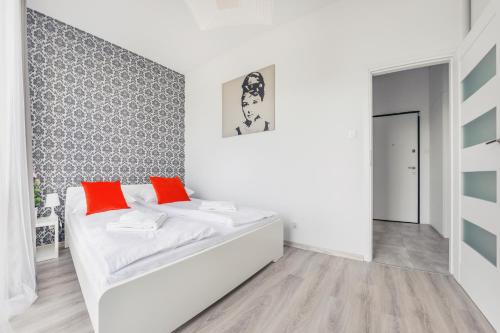 biały pokój z łóżkiem z pomarańczowymi poduszkami w obiekcie Apartamenty Sun & Snow Mila Baltica w Gdańsku
