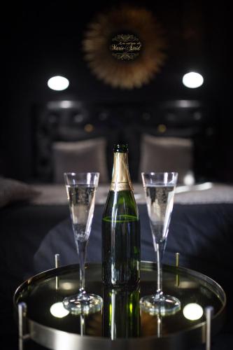 - une bouteille de champagne et deux verres sur une table dans l'établissement Les Secrets de Marie-Astrid, Suite Love Room, à Bordeaux
