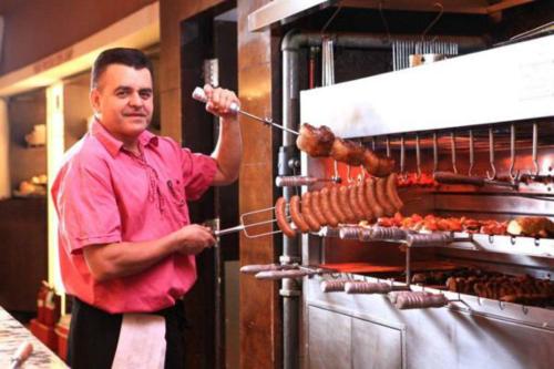 a man is pulling meat from an oven at V-Continent Beijing Parkview Wuzhou Hotel in Beijing