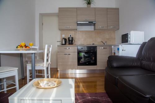 a living room with a black couch and a kitchen at Apartments Victoria in Dubrovnik