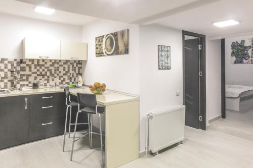 a kitchen with black cabinets and a counter with stools at Victoria Duplex Apartament in Bucharest