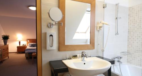 a bathroom with a sink and a mirror and a tub at King's and Lake's House Golf Course Royal Bled in Bled