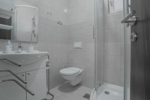 a white bathroom with a toilet and a sink at Apartments Maritea in Vodice