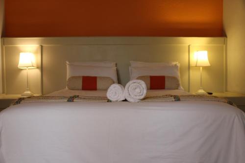 a bedroom with a white bed with two towels on it at Makarios Lodge in Polokwane