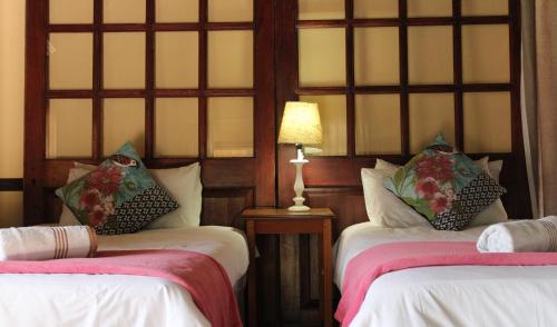 a bedroom with two beds and a lamp on a table at Makarios Lodge in Polokwane