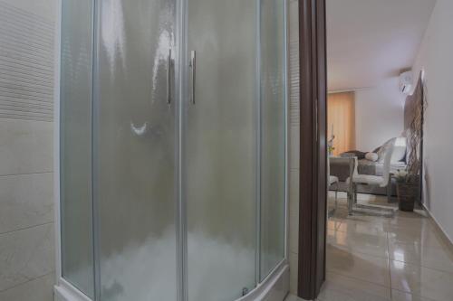 a glass shower in a bathroom with a living room at Apartments Maritea in Vodice