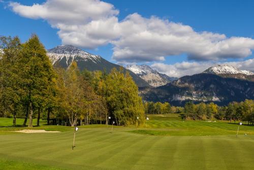 a golf course with snow capped mountains in the background at King's and Lake's House Golf Course Royal Bled in Bled