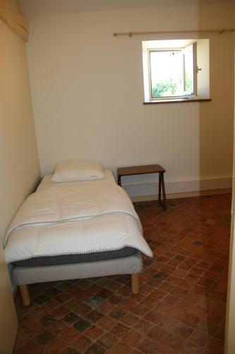 a bed in a room with a small window at Le Gite du Grand Saulaie in Chambellay