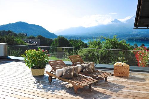 a deck with two benches and a view of a mountain at Biohof Naturzeit Faaker See in Drobollach am Faakersee