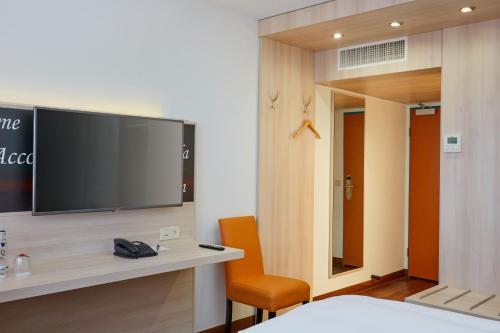 a hotel room with a tv on a wall at H+ Hotel Stuttgart Herrenberg in Herrenberg