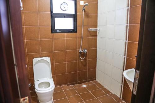a bathroom with a toilet and a window and a sink at Barka Hotel Apartment in Samhān
