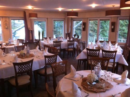 une salle à manger avec des tables blanches, des chaises et des fenêtres dans l'établissement Hotel Peiler Garni, à Iserlohn