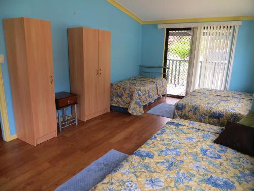 two beds in a room with blue walls and wooden floors at Orchid Beach Retreat Orchid Beach Fraser Island in K'gari Island (Fraser Island)