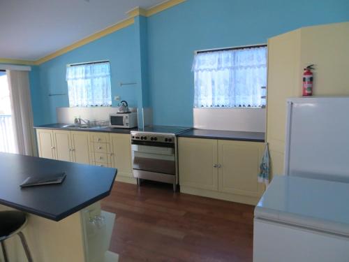 a kitchen with blue walls and a white refrigerator at Orchid Beach Retreat Orchid Beach Fraser Island in K'gari Island (Fraser Island)