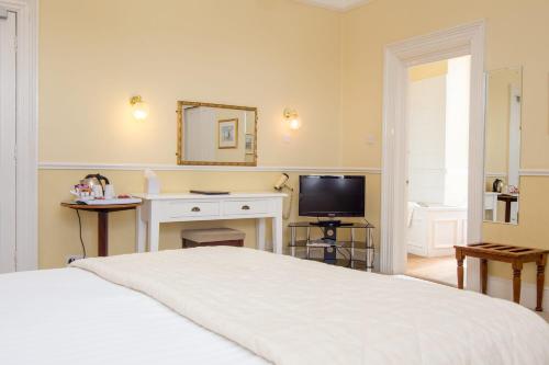 a bedroom with a bed and a desk and a television at The Queens Hotel in Penzance