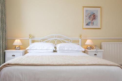 a bedroom with a white bed with white pillows at The Queens Hotel in Penzance